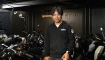 ホワイトベースの店内でバイクと写る人物